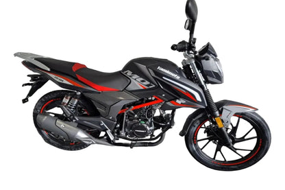 A black and red yamimoto motorcycle parked in a garage corner with a white brick wall and gray floor.