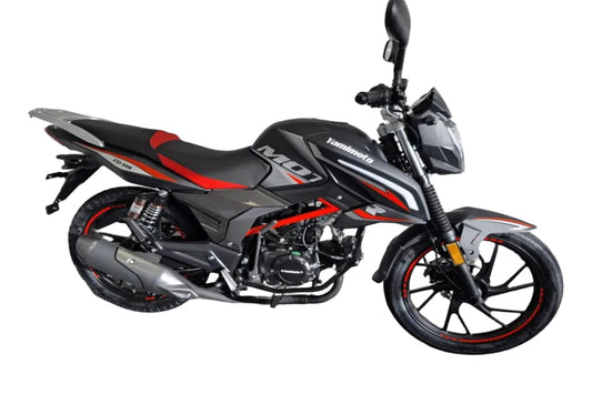 A black and red yamimoto motorcycle parked in a garage corner with a white brick wall and gray floor.